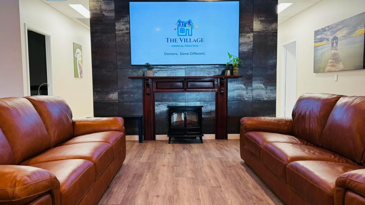 The living room at The Village: leather sofas around a fireplace